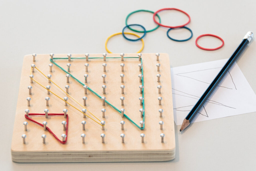 bunte Gummibänder die auf einem Nagelbrett gespannt sind