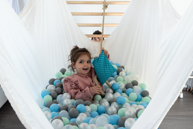 Kind im Bällebad einer Hängematte